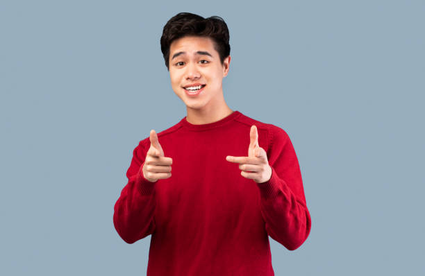 istock Happy asian guy pointing fingers at camera at studio 1291770269
