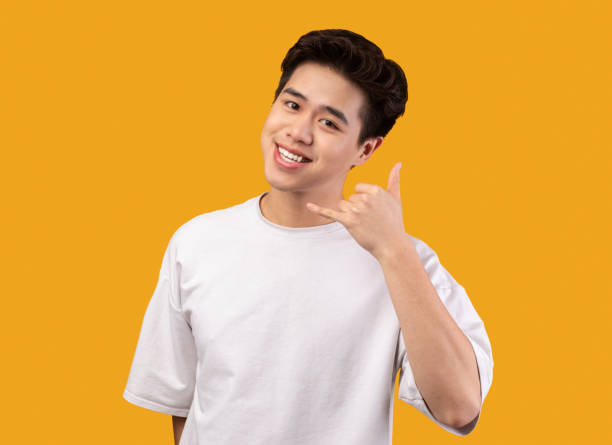 Smiling asian man doing call me phone gesture