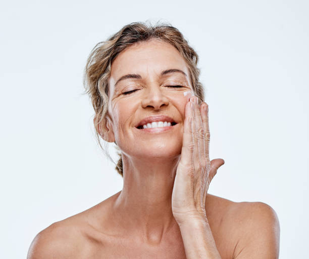 We'd do anything to keep that beautiful glow Shot of a mature woman posing with moisturiser on her face moisturizer stock pictures, royalty-free photos & images