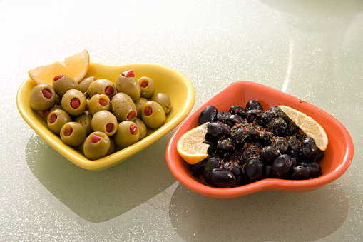 Close up indoor shot of green and black olives in ceramic plates on modern domestic kitchen table