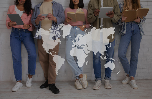 Education, international relations and student exchange. Young multiracial people with books and gadgets read, over white brick wall background, double exposure with world map, collage, cropped