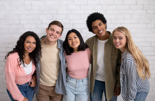 Friendship of exchange students and modern education Friendship of exchange students and modern education. Happy young multiracial people team in casual hugging in college or university, smiling and looking at camera, on white brick wall background multi ethnic group college student group of people global communications stock pictures, royalty-free photos & images