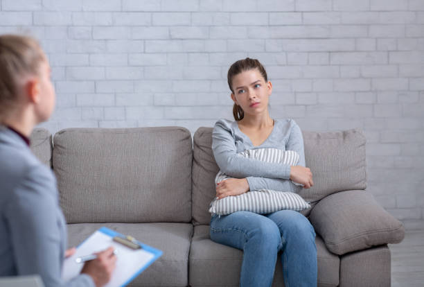 istock Desperate young woman suffering from nevrous breakdown, sitting on couch at psychologist's office and hugging pillow 1291773036