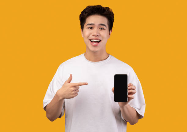 istock Asian guy showing blank smartphone screen and pointing 1291775835