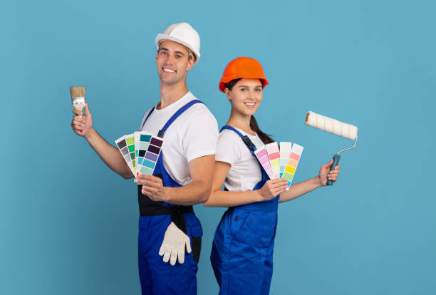 改築。色見本と絵画ブラシでポーズをとる若い画家のカップル - female house painter home decorator paintbrush ストックフォトと画像