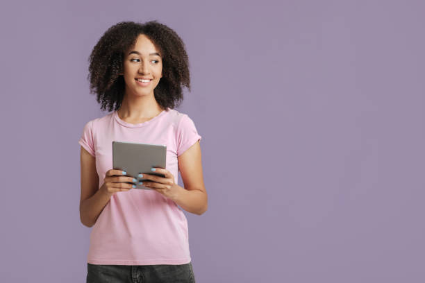 istock Technology for work and study. Smiling female in casual, holds tablet, makes online shopping 1291776648