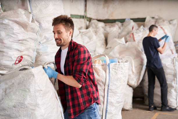 istock Man moves heavy garbage bags with wastes 1291778021