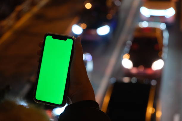 istock hand holding green screen smart phone with blurred traffic at night 1291781622
