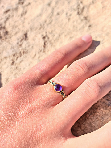 female hand with boho ring with violet stone