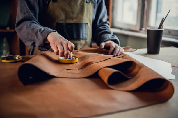 Experienced specialist in the production of footwear leather lays on a table in his workshop stock photo