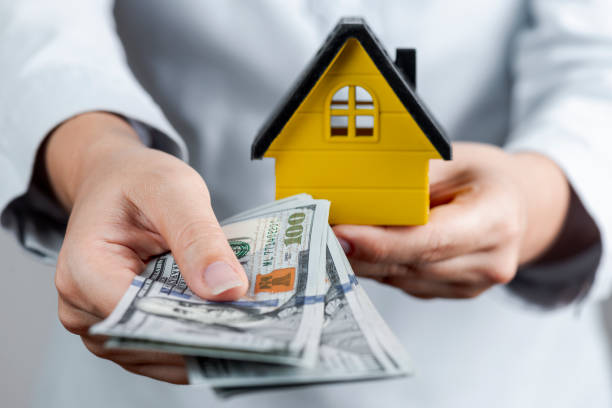 istock Woman Holding Dollars And Model House 1291784431