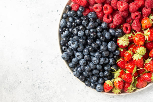 istock Fresh berries. Different berries in a white ceramic plate on a light table. Strawberries, raspberries and blueberries on a plate. Top view with space for text 1291786013