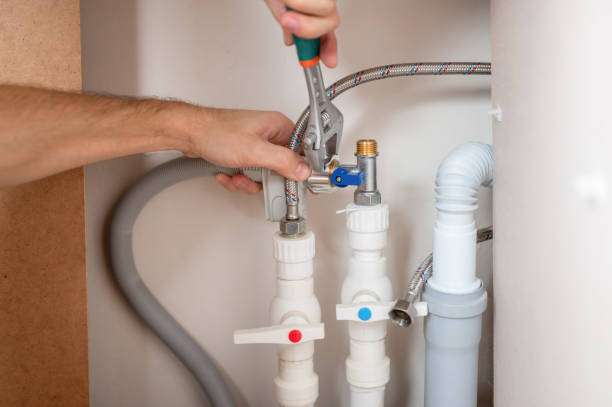 un hombre utiliza una llave ajustable para instalar una manguera de suministro de agua en el lavavajillas. - silverware clean wet kitchen utensil fotografías e imágenes de stock