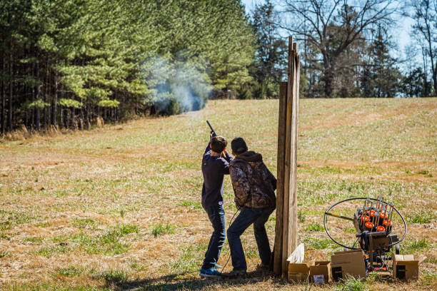 Target Shooting Practice Woodland, GA / USA - February 13, 2016: A teenage boy receives safety and procedure training by an adult mentor while practicing firearm usage. trap shooting stock pictures, royalty-free photos & images