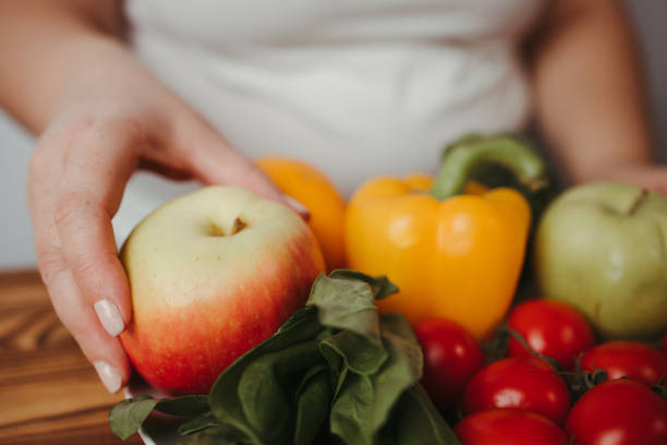istock Fat woman snacking with fruits and vegetables 1291788883