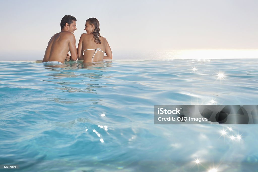 Souriant couple à la recherche dans chacun d'autres dans la piscine - Photo de Femmes libre de droits