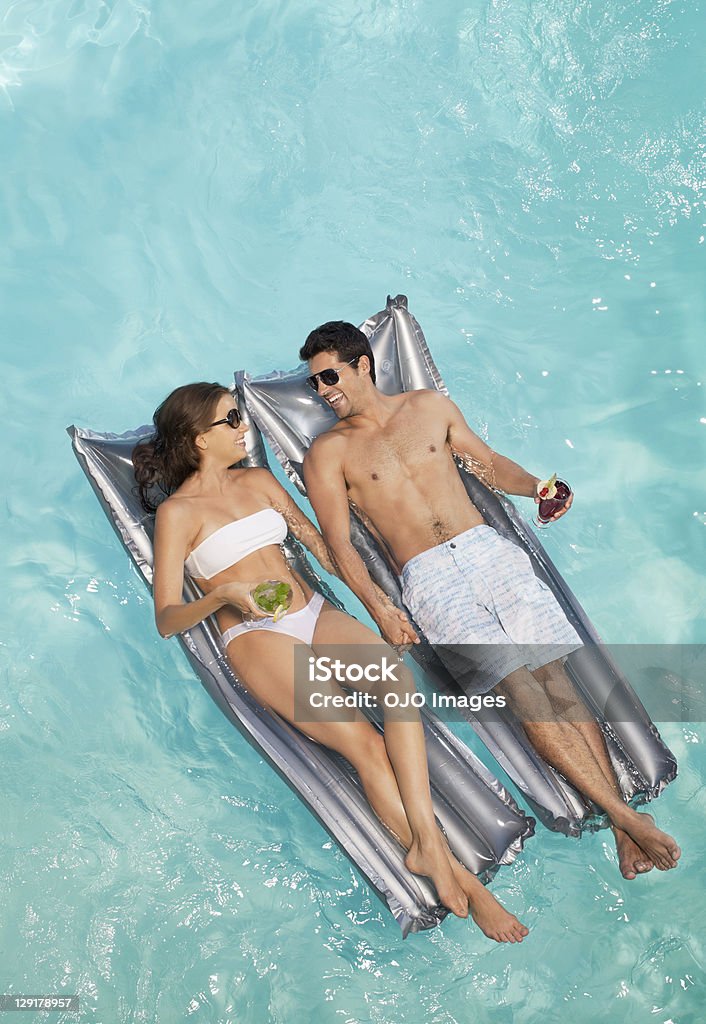 Sonriente pareja acostado de serie Mientras sostiene de vidrio - Foto de stock de Piscina libre de derechos