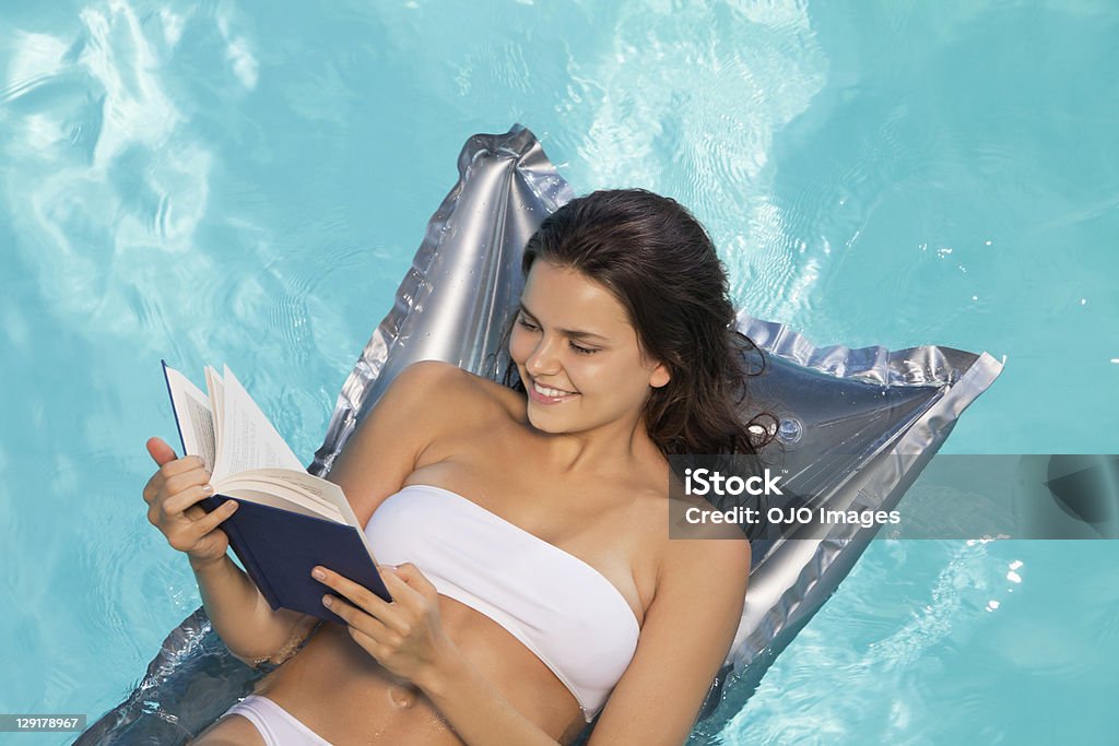 Veduta dall'alto di donna sorridente leggendo un libro - Foto stock royalty-free di Bikini
