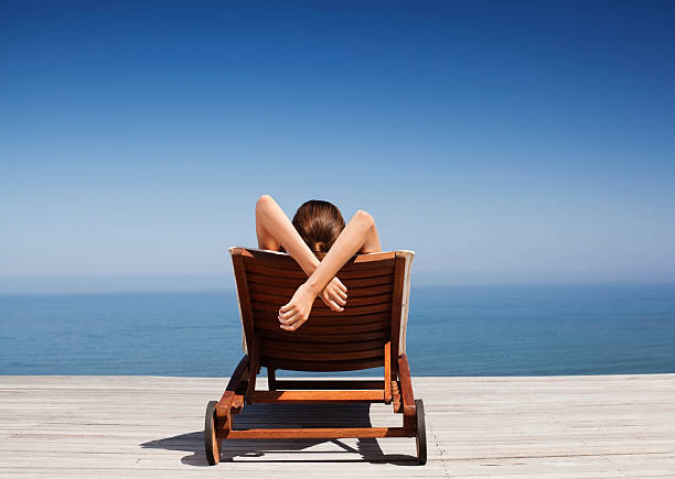Rear view of woman on deck chair  deck chair stock pictures, royalty-free photos & images