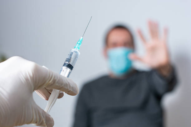 istock Close up of unrecognizable doctor trying to vaccinate its patient while he is refusing it 1291790627