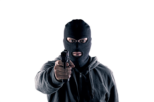 Criminal wearing black balaclava and hoodie with a gun isolated on white with clipping path