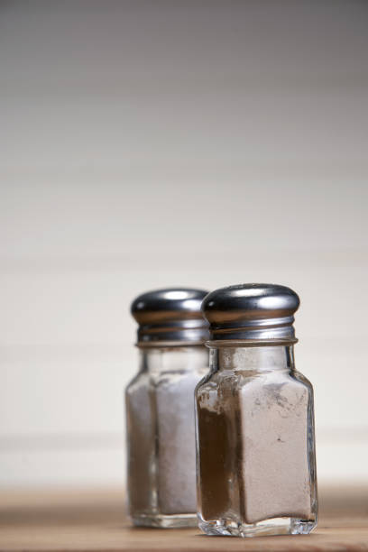 istock Salt and pepper shaker on wooden table against white wall 1291793312