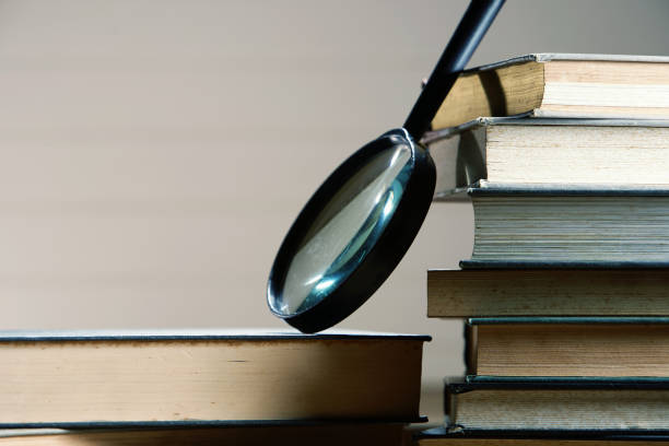 istock Searching... stack of book  with magnifier glass, side view 1291793536