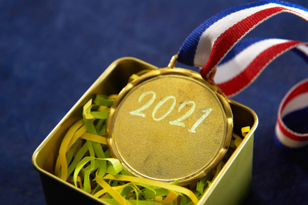 Gold medal with "2021", blue red and white ribbon is attached to the medal in a box on blue background Gold medal with "2021", blue red and white ribbon is attached to the medal in a box on blue background record breaking stock pictures, royalty-free photos & images