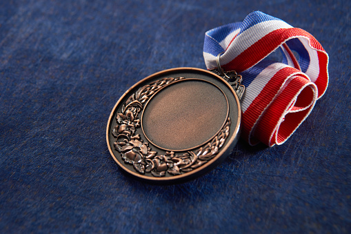 bronze medal with ribbon on blue background