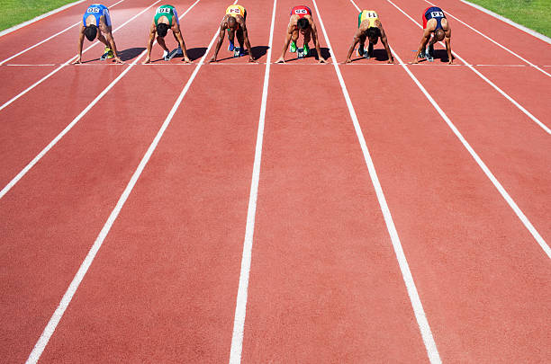 homens em um bloco inicial em uma pista de atletismo - running track imagens e fotografias de stock