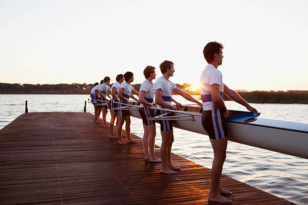 vista lateral de homens segurando barco - rowing team sport team sport rowing - fotografias e filmes do acervo
