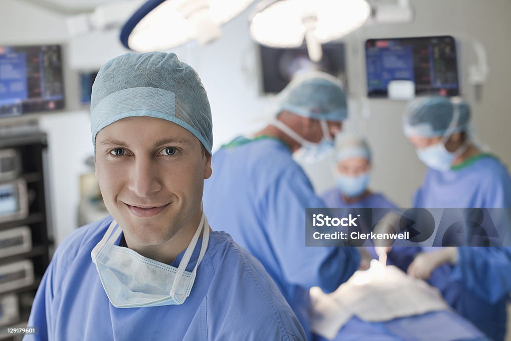 Ritratto di sorridente giovane medico in sala operatoria - Foto stock royalty-free di Sala operatoria