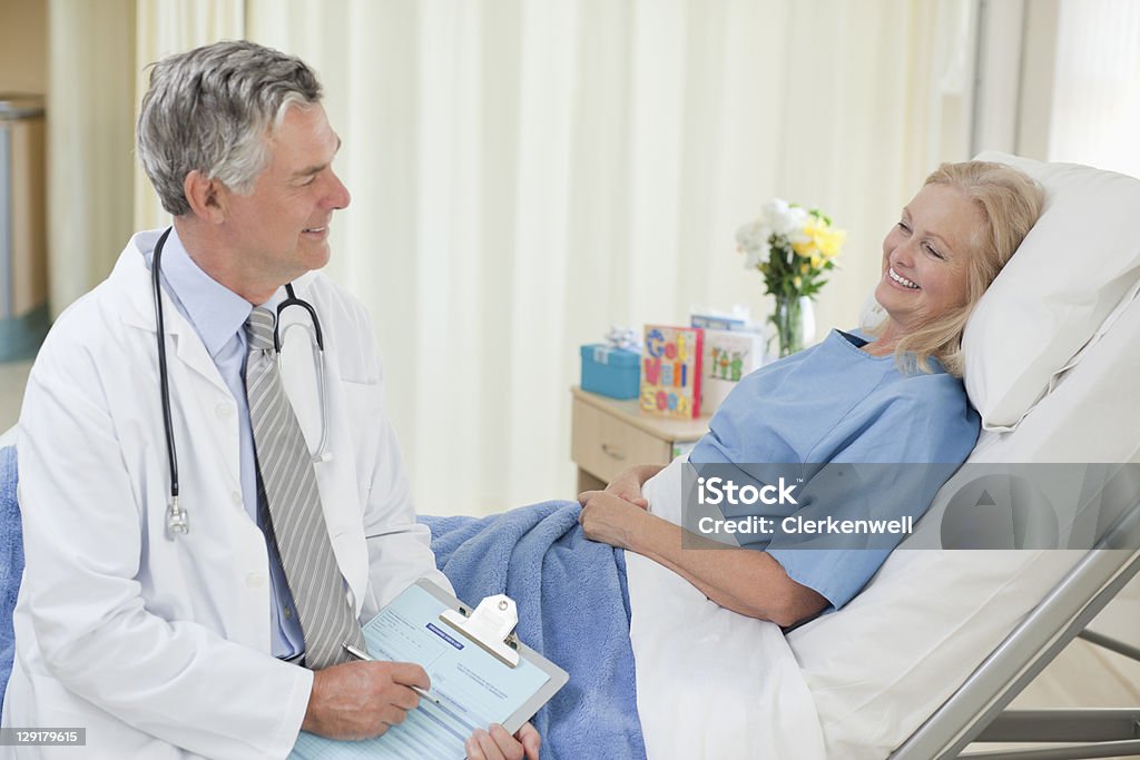 Улыбается Старший доктор, говорящий с пациентом - Стоковые фото 60-64 года роялти-фри