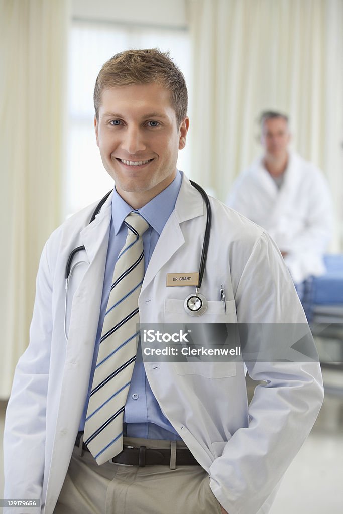 Retrato de hombre joven médico con paciente en el fondo - Foto de stock de Doctor libre de derechos