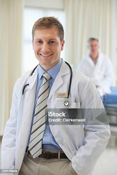 Retrato De Hombre Joven Médico Con Paciente En El Fondo Foto de stock y más banco de imágenes de Doctor