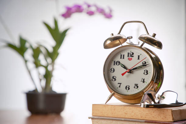 istock vintage alarm clock and reading glass on stack of book 1291797855