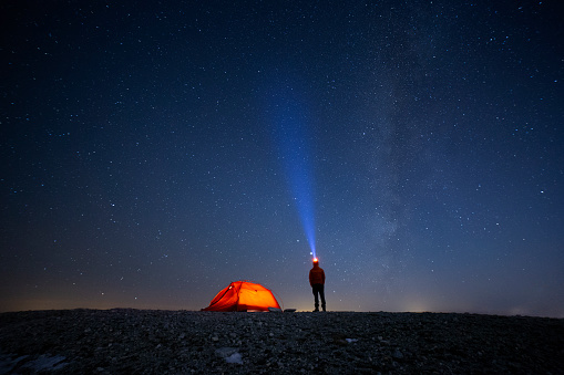 mountaineer and camping tent under the stars at night