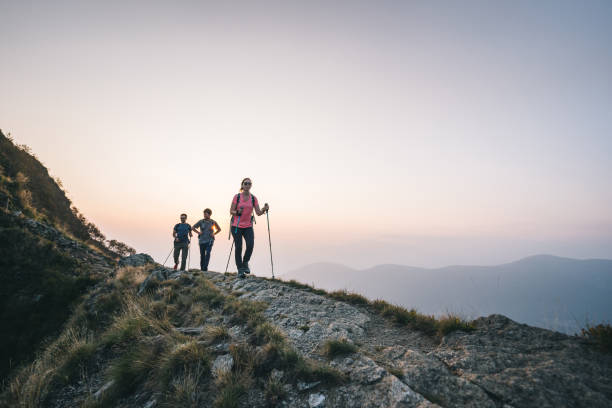 Friends hike along sunny mountain ridge at sunrise