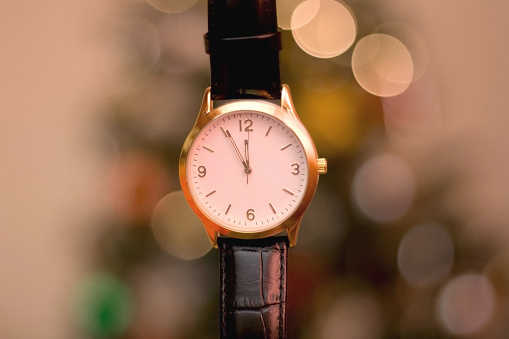 Wrist watch with needles approaching midnight. New Year's Eve concept. Selective focus, festive hooliday background.