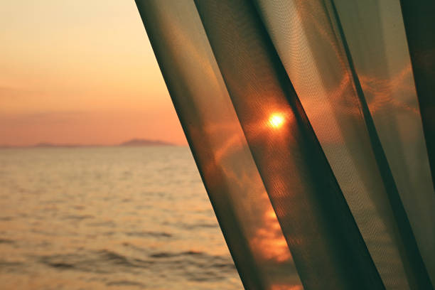The Bright Sun Shining Through the Curtain with Blurry Sea in Background