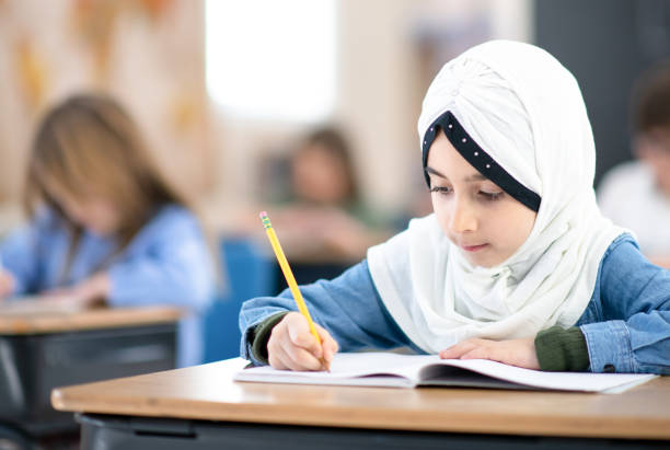 istock Muslim Girl Writing in her Notebook in Class 1291815666