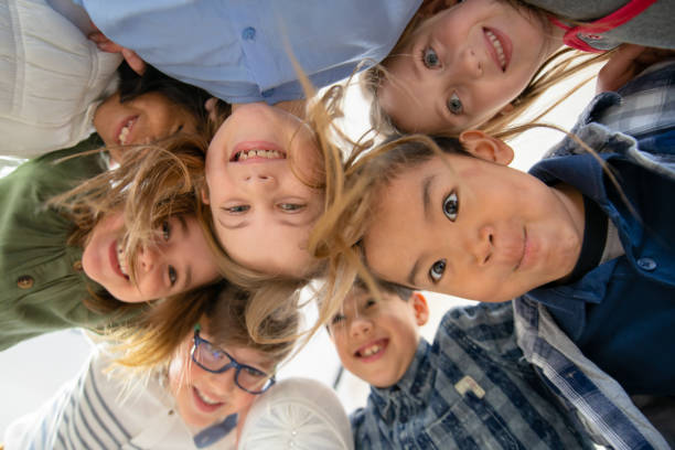 istock An Adorable Group of Diverse Kids Look Down at Camera While Huddled Together 1291815672