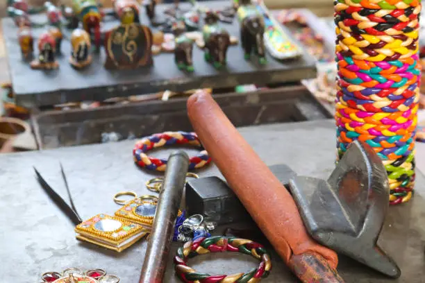 Photo of Selective Focus On Equipments And Setup Of Making Of Handmade Crafted Famous Popular Indian Lac Or Lakh Bangles Choodiyan Chudiyan With Finished Prepared Bracelets In Blur Background