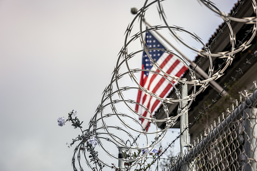 Concept of political isolationism and economic slowdown in the United States of America. Flag behind barbed wire.