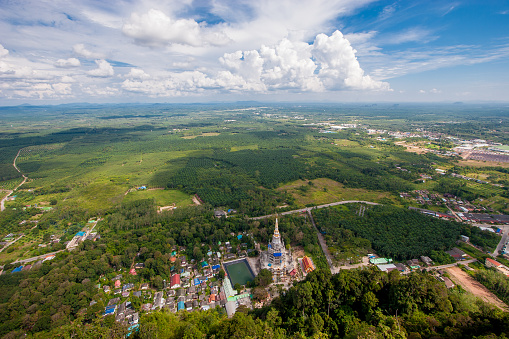 Aerial view of the Tiger Cave temple. Green fields and clouds against blue sky.