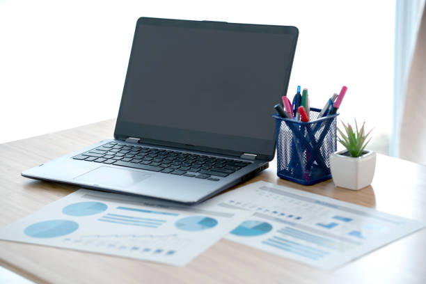 istock Laptop and papers on desk in front of window 1291821902