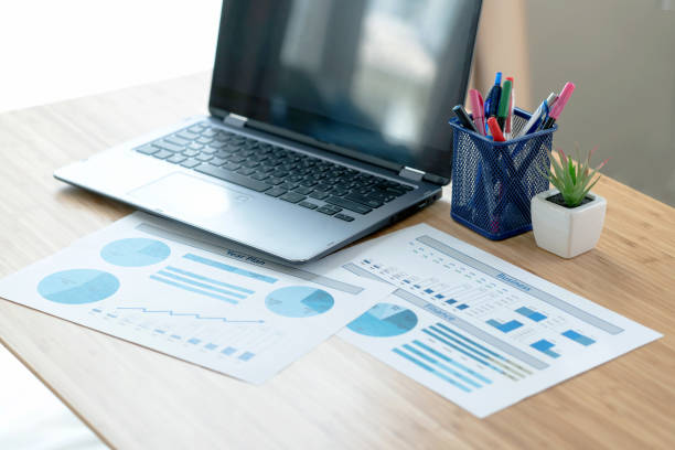 istock Laptop and papers on desk in front of window 1291821945