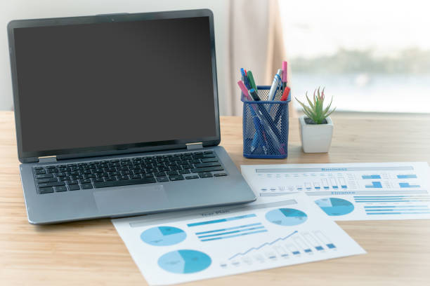 istock Laptop and papers on desk in front of window 1291821955