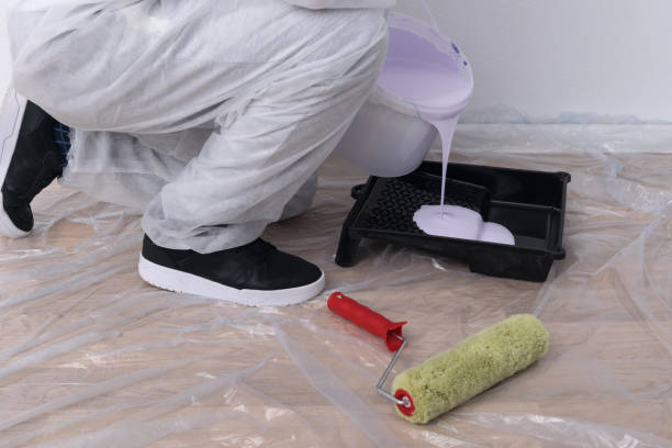 istock the painter pours paint from a bucket into a bath for applying to brushes and a roller 1291824052