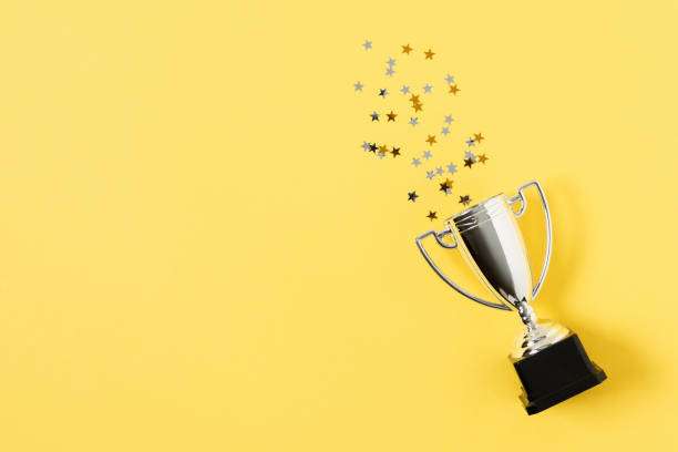 istock Winner or champion silver trophy cup on yellow background top view. 1291825198